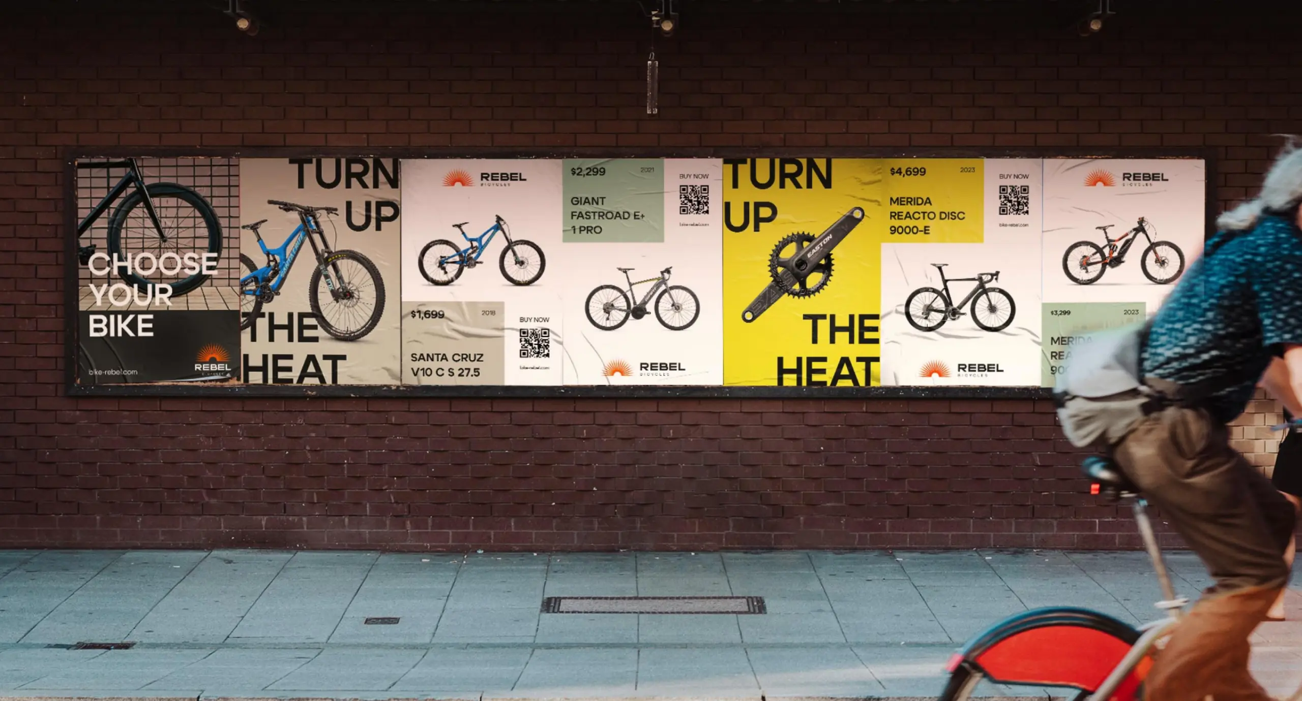 Фірмові постери магазину велосипедів Rebel Bicycles на стіні будівлі, повз яку проїжджає велосипедист.